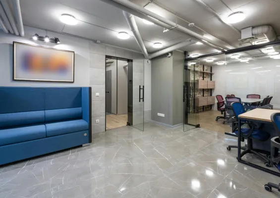 An Office With blue couch and office chairs aligned in an office table. A grey-painted walls in the office on a tile Flooring